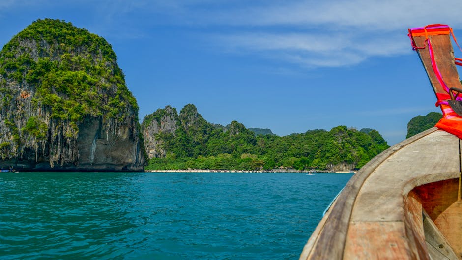 Explore the stunning limestone cliffs and turquoise waters of Krabi, Thailand, from a traditional longtail boat.